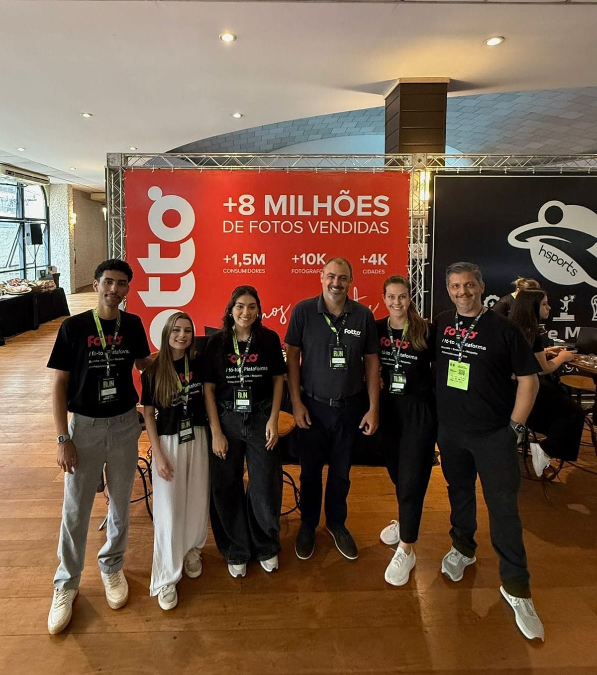 Equipe da Fotto posa sorridente em frente ao estande da marca na Run Expo 2025
