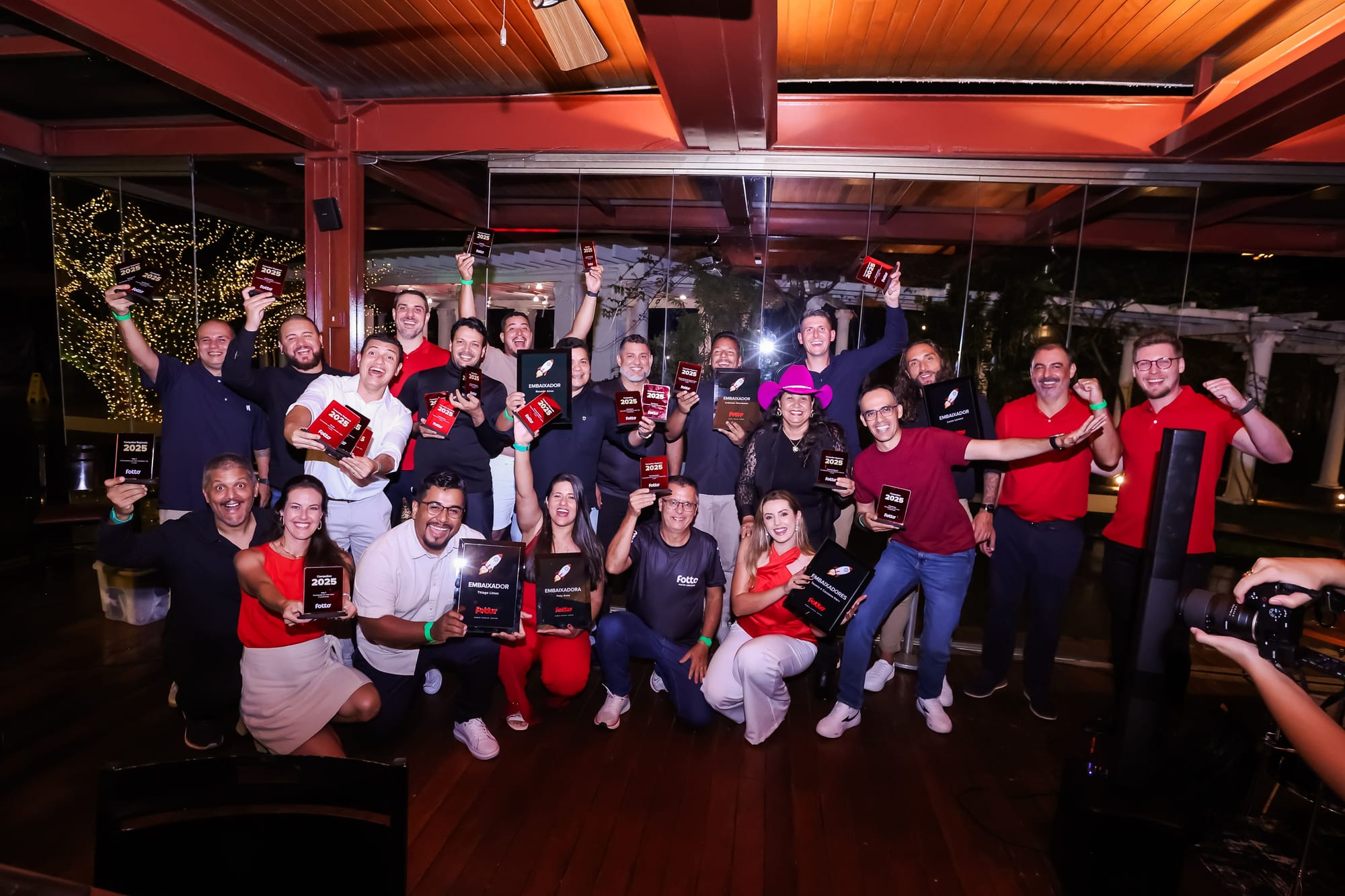 Fotógrafos Fotto sorrindo para a foto segurando troféus. Todos estão celebrando a premiação no jantar do Encontro Estratégico Fotto.